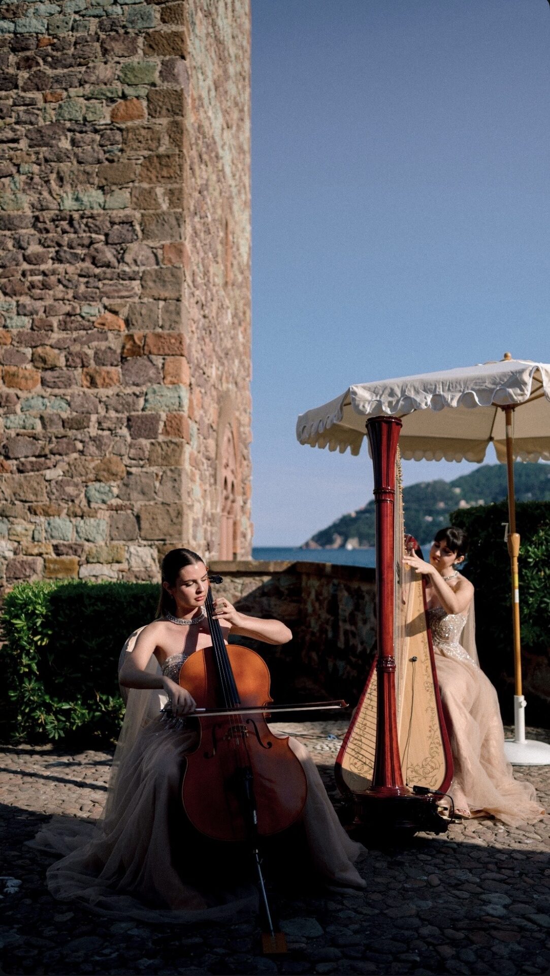 Violoncelliste et harpiste jouant en soirée près d'un château en bord de mer